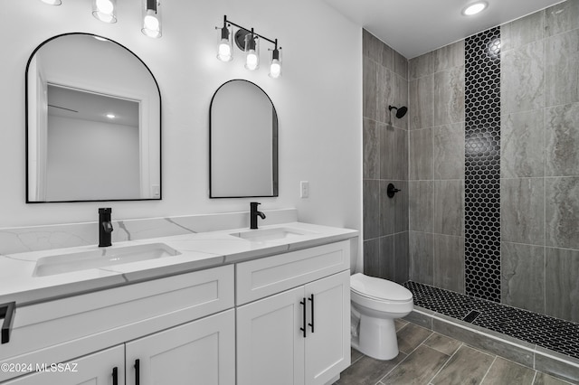 bathroom featuring tiled shower, vanity, and toilet