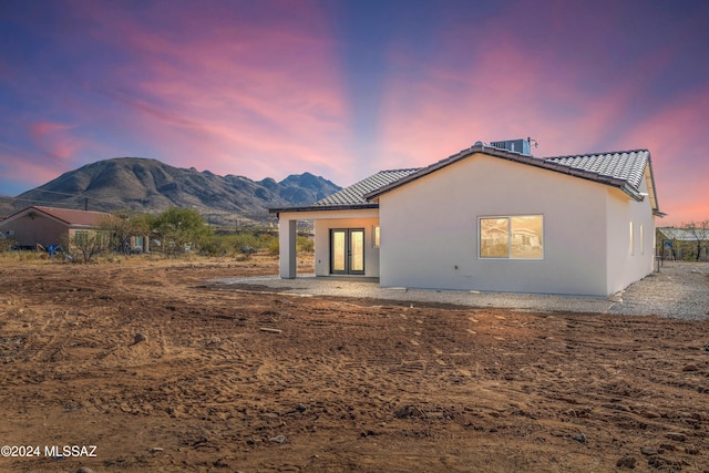 back house at dusk with a mountain view and french doors