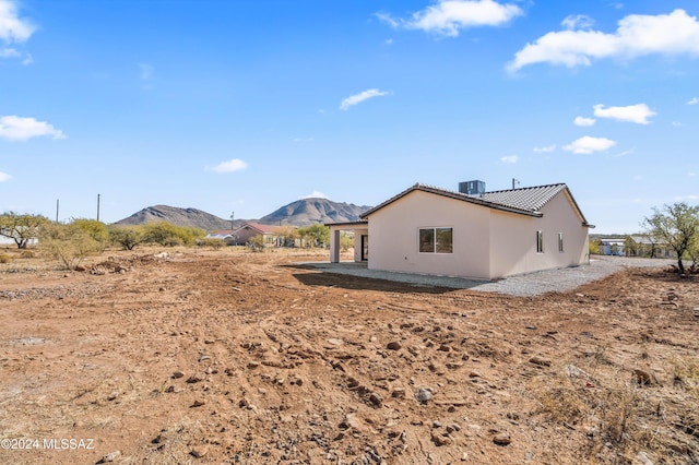 back of property with a mountain view, central AC, and a patio area