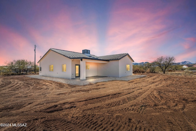 back house at dusk with a mountain view, a patio area, and central air condition unit