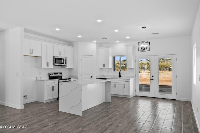 kitchen featuring appliances with stainless steel finishes, white cabinetry, a kitchen island, and light hardwood / wood-style flooring