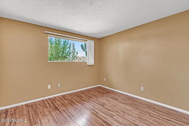 unfurnished room with light wood-type flooring and a textured ceiling