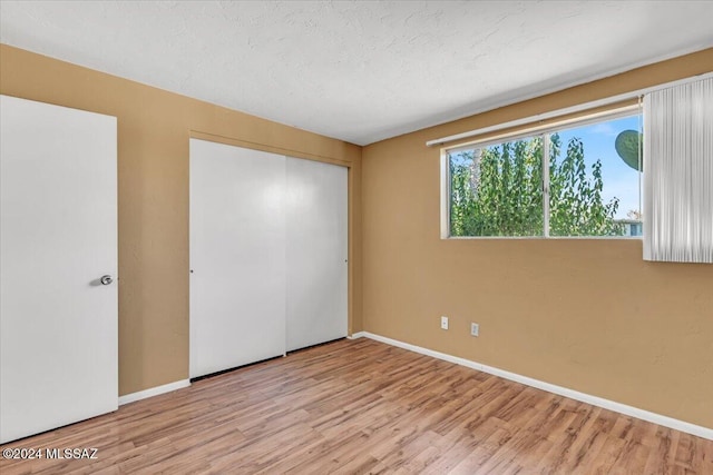 unfurnished bedroom featuring a closet, light hardwood / wood-style flooring, and a textured ceiling