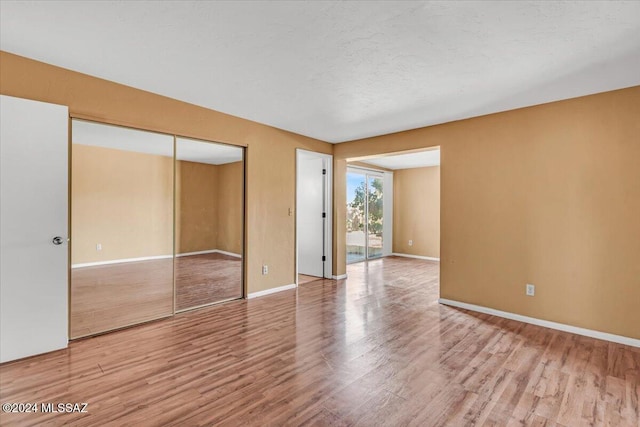 spare room featuring a textured ceiling and light hardwood / wood-style flooring