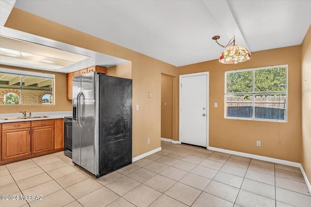 kitchen featuring sink, hanging light fixtures, stainless steel fridge, stove, and light tile patterned flooring