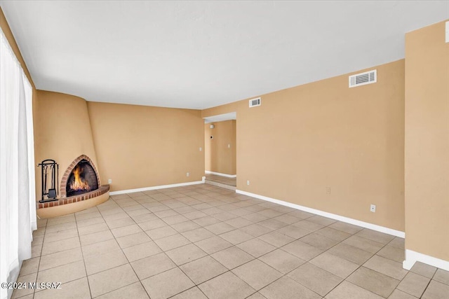 unfurnished living room with light tile patterned floors and a brick fireplace