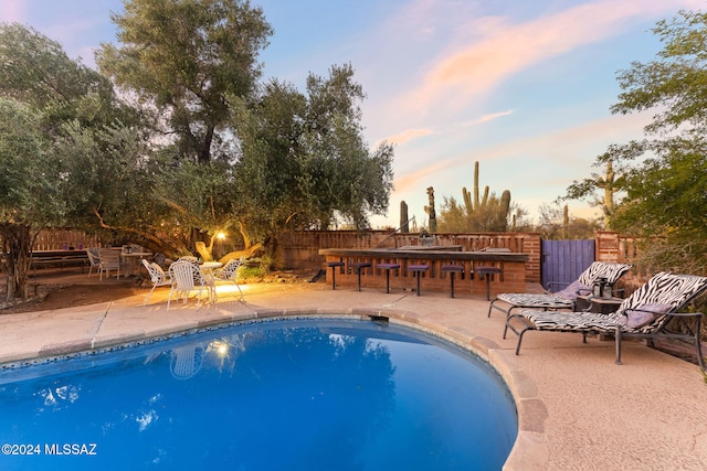 pool at dusk featuring a patio area