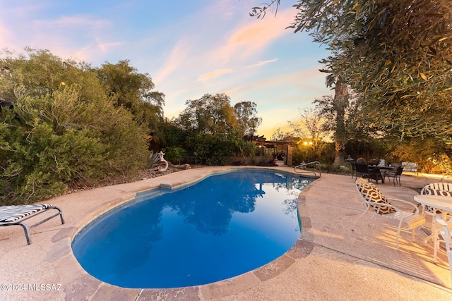 pool at dusk with a patio area