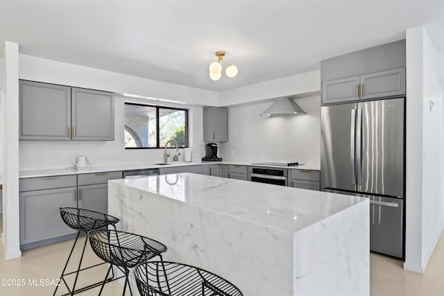 kitchen featuring stainless steel appliances, a center island, light stone countertops, and wall chimney range hood