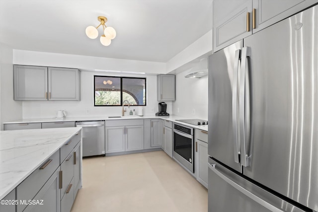 kitchen with appliances with stainless steel finishes, sink, gray cabinetry, and light stone counters