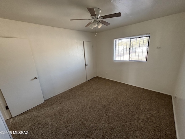 empty room featuring ceiling fan and dark colored carpet