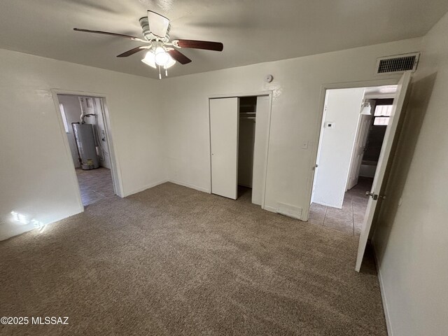 unfurnished bedroom with light carpet, ensuite bathroom, gas water heater, ceiling fan, and a closet