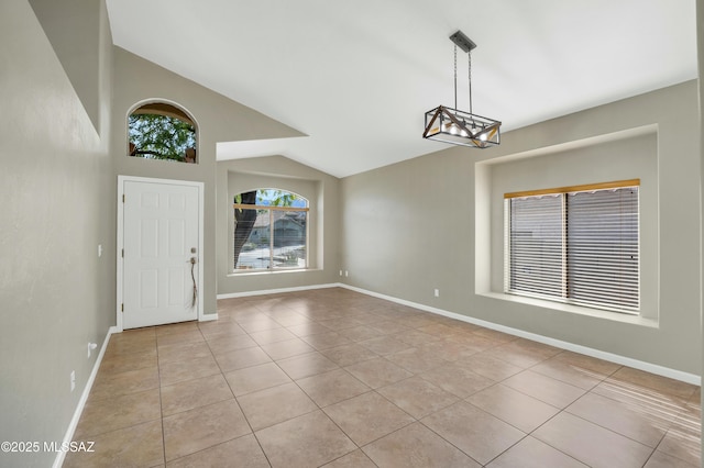 tiled entryway featuring an inviting chandelier and vaulted ceiling