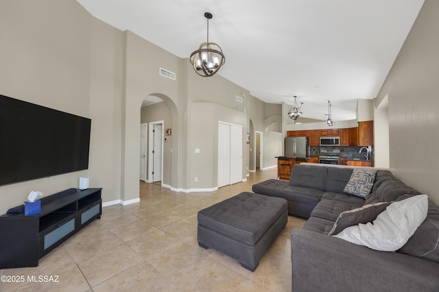 living room featuring light tile patterned floors, high vaulted ceiling, an inviting chandelier, and sink