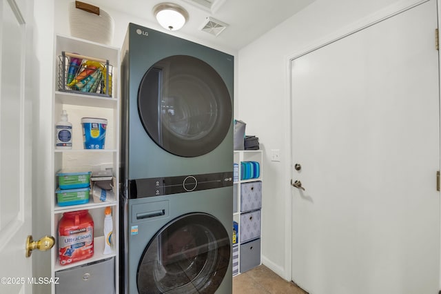 clothes washing area featuring stacked washer and dryer and light tile patterned flooring