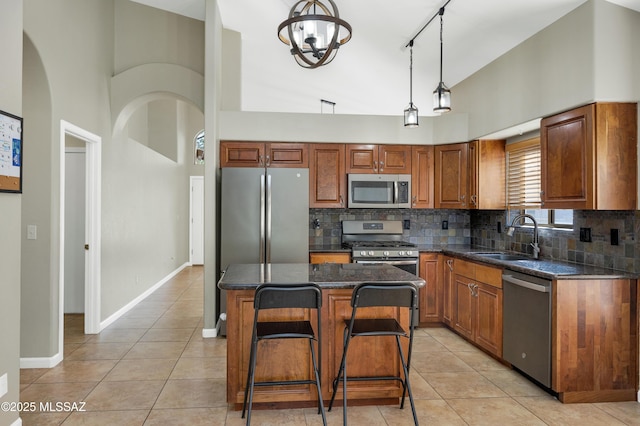 kitchen with pendant lighting, sink, light tile patterned floors, appliances with stainless steel finishes, and a kitchen island