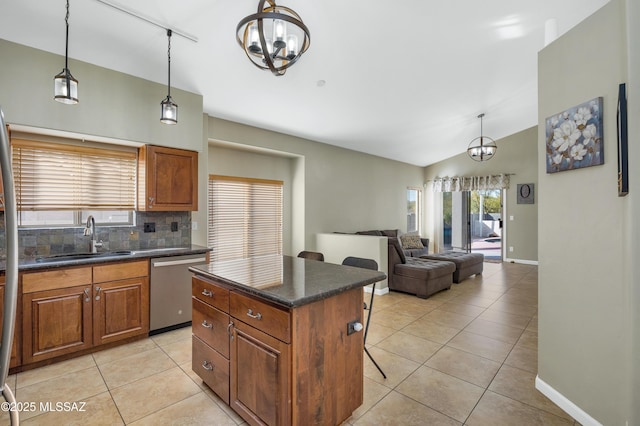 kitchen with sink, a breakfast bar area, decorative light fixtures, stainless steel dishwasher, and a kitchen island