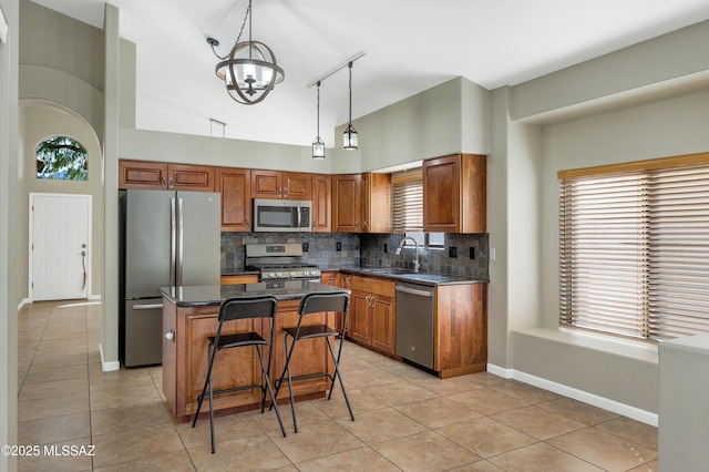 kitchen featuring stainless steel appliances, sink, a center island, hanging light fixtures, and light tile patterned flooring