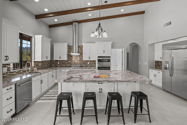 kitchen featuring sink, appliances with stainless steel finishes, a large island, beam ceiling, and white cabinetry