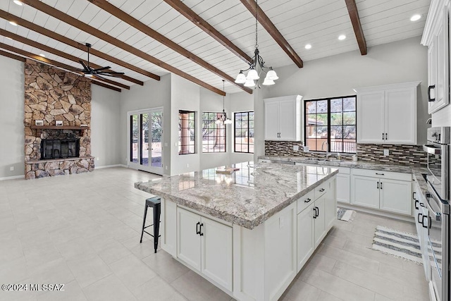 kitchen featuring a fireplace, white cabinets, a kitchen island, and stainless steel oven