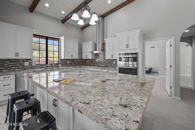 kitchen featuring pendant lighting, light stone counters, white cabinetry, and appliances with stainless steel finishes