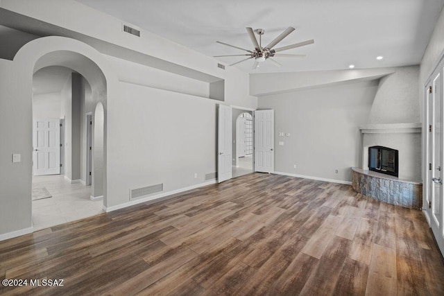 unfurnished living room with ceiling fan, a large fireplace, wood-type flooring, and lofted ceiling