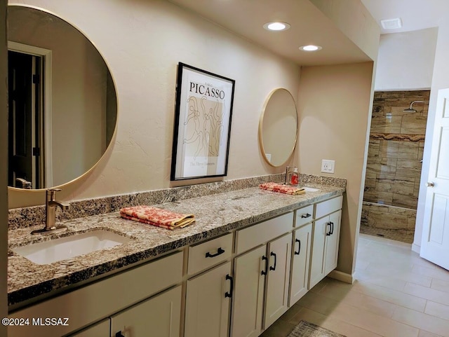 bathroom with tile patterned flooring, vanity, and tiled shower