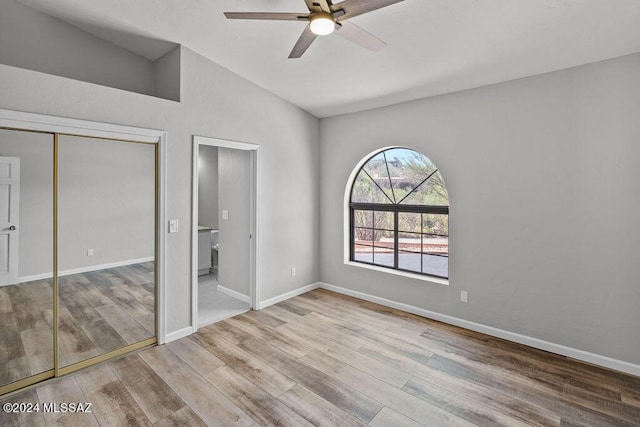 unfurnished bedroom featuring ceiling fan, lofted ceiling, light hardwood / wood-style flooring, and a closet