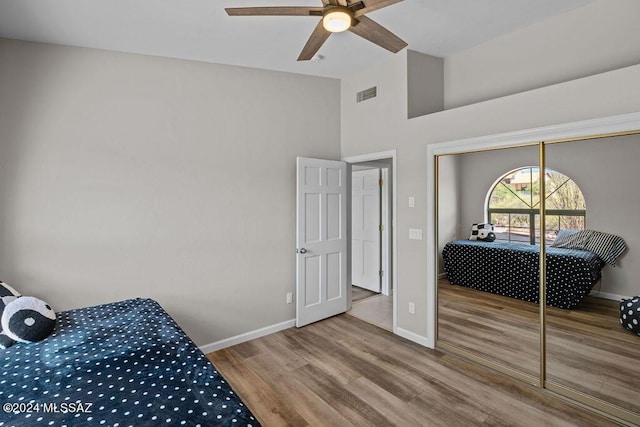 bedroom featuring a high ceiling, hardwood / wood-style flooring, a closet, and ceiling fan