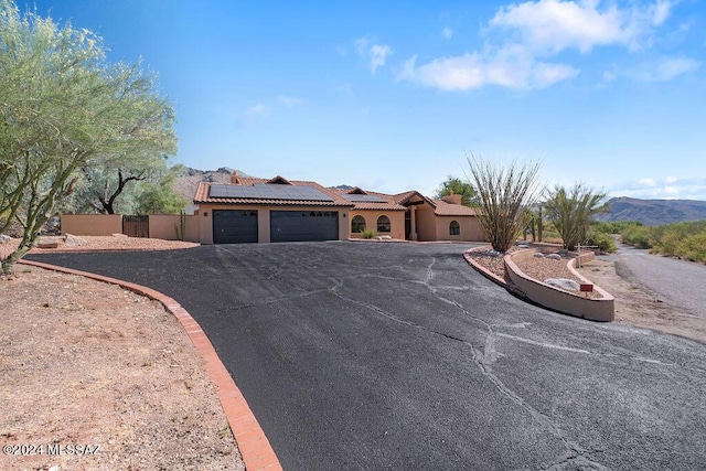 view of front of property featuring a mountain view, a garage, and solar panels