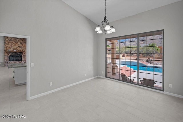 unfurnished room featuring a stone fireplace, light tile patterned floors, vaulted ceiling, and a notable chandelier