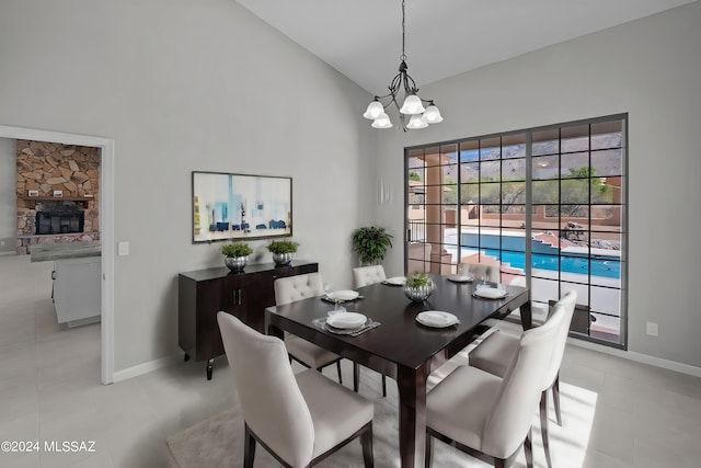 dining space featuring a fireplace, light tile patterned floors, high vaulted ceiling, and a notable chandelier