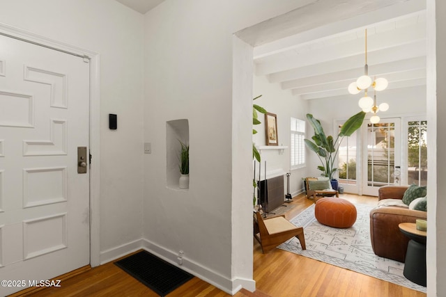 foyer entrance featuring a notable chandelier, beam ceiling, and wood-type flooring