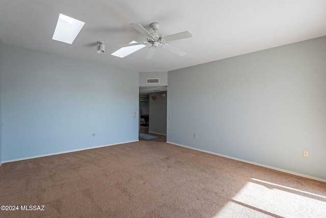 spare room featuring carpet, ceiling fan, and a skylight