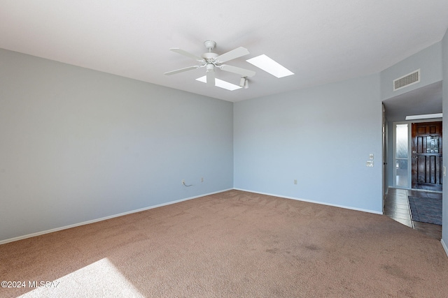 empty room featuring ceiling fan, carpet floors, and a skylight