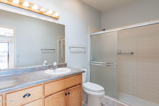 bathroom with tile patterned floors, vanity, toilet, and a shower with door