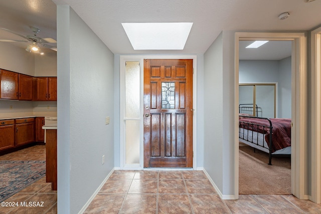 foyer entrance featuring ceiling fan, light colored carpet, and a skylight