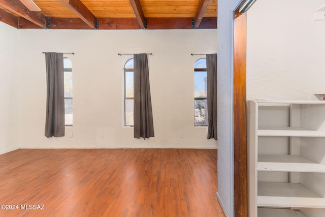 empty room with beam ceiling, wooden ceiling, and hardwood / wood-style floors