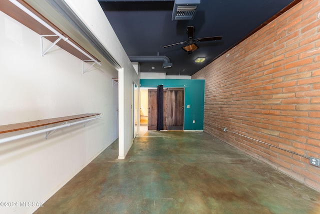 interior space featuring ceiling fan and brick wall