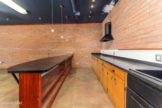 interior space with exhaust hood, hanging light fixtures, and brick wall