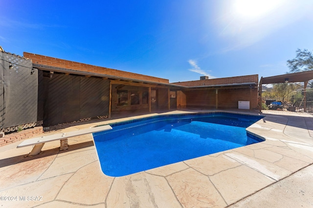 view of pool with a diving board and a patio area