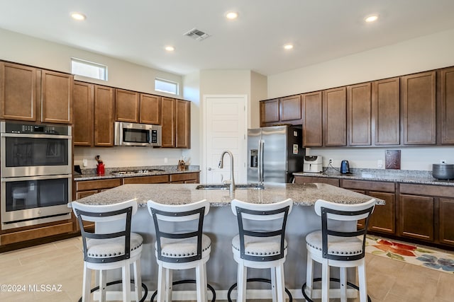 kitchen featuring a breakfast bar, stainless steel appliances, a kitchen island with sink, and sink