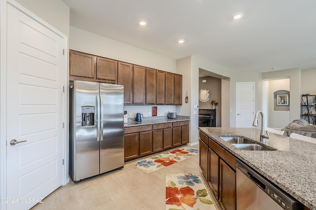 kitchen with light tile patterned floors, light stone countertops, sink, and appliances with stainless steel finishes