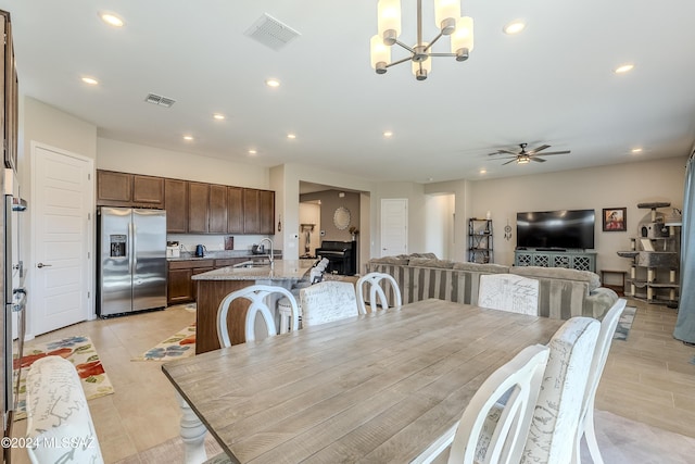 dining room with sink and ceiling fan with notable chandelier