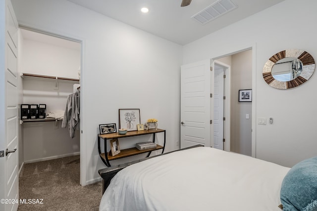 carpeted bedroom with a walk in closet, ceiling fan, and a closet