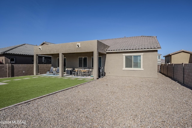 back of property with a lawn and a patio area