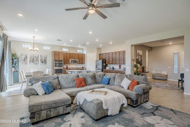 living room featuring light tile patterned floors and ceiling fan with notable chandelier