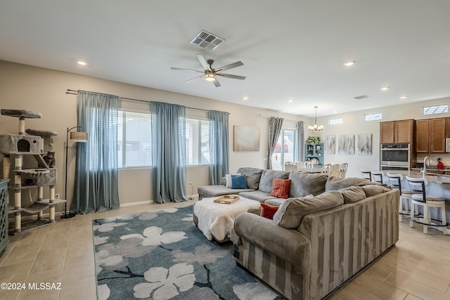 living room featuring ceiling fan with notable chandelier and light wood-type flooring