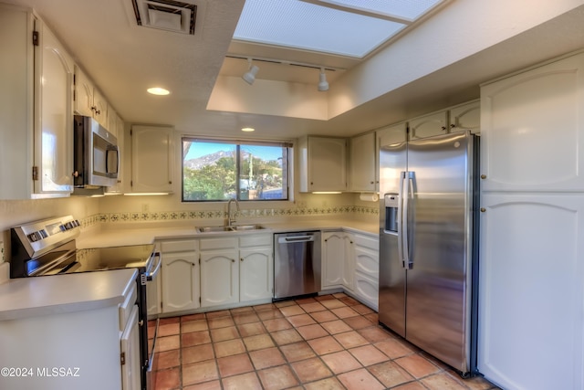 kitchen with sink, rail lighting, stainless steel appliances, backsplash, and white cabinets