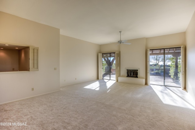 unfurnished living room with a wealth of natural light, light colored carpet, and ceiling fan